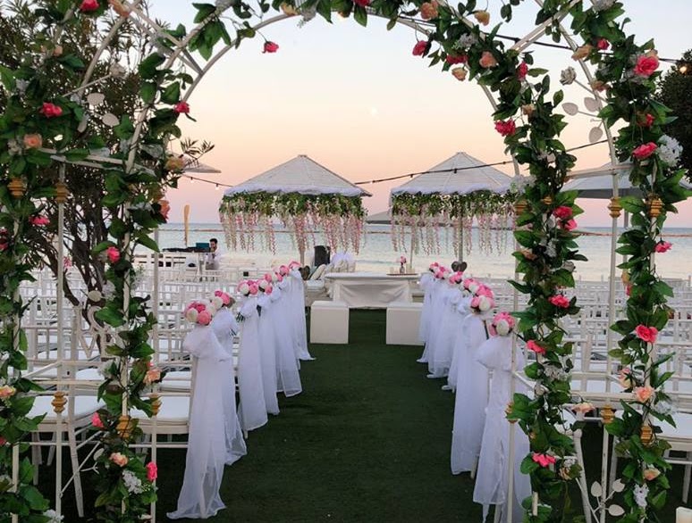 a wedding ceremony with white chairs and flowers