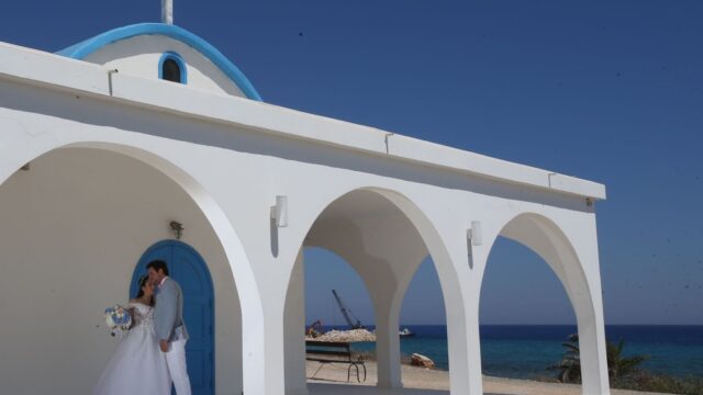 a man and woman kissing in front of a white building