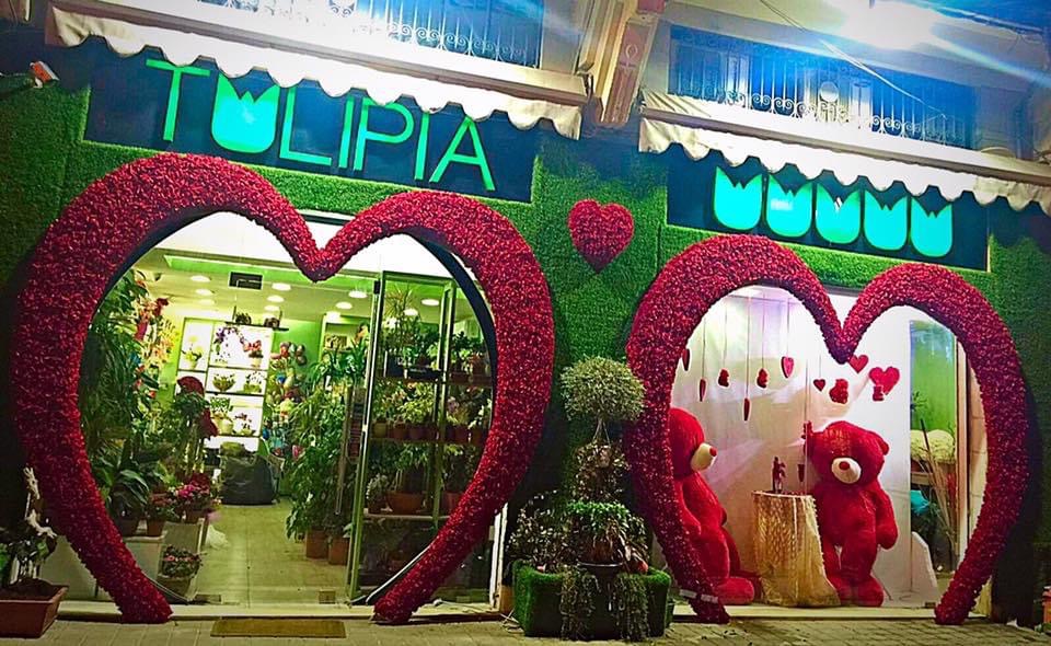 a store front with a heart shaped sign and teddy bears