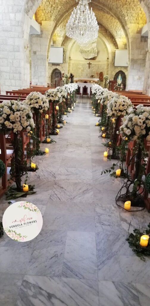 a church aisle with white flowers and candles