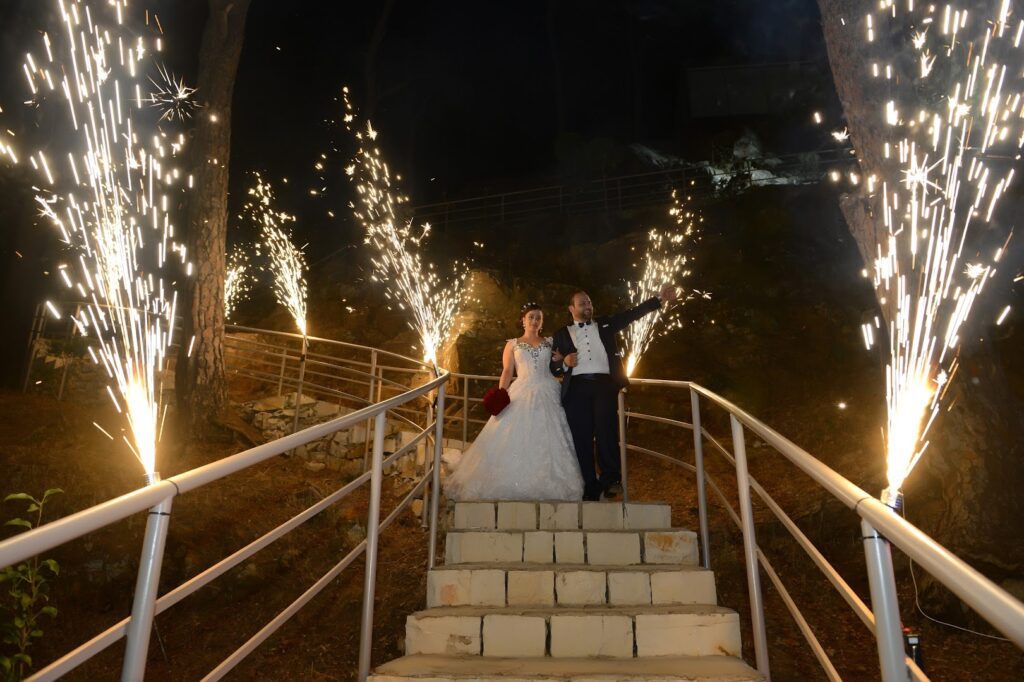 a man and woman standing on stairs with fireworks in the background