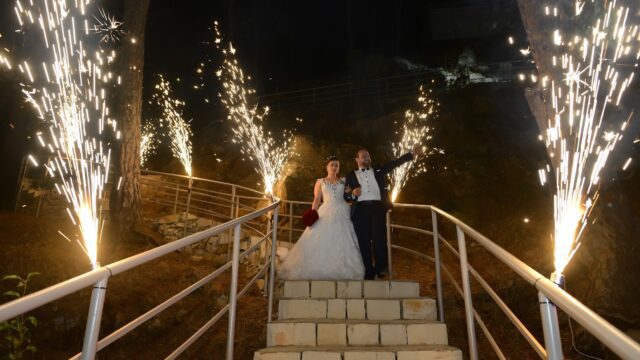 a man and woman standing on stairs with fireworks in the background