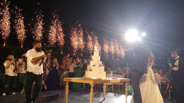 a couple of people standing on a stage with a cake and a crowd of people