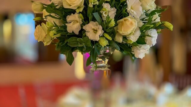 a bouquet of white roses in a tall glass vase