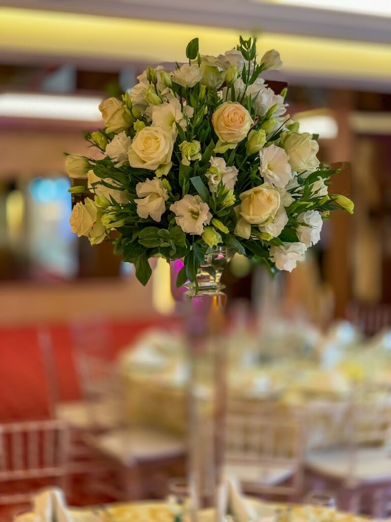 a bouquet of white roses in a tall glass vase