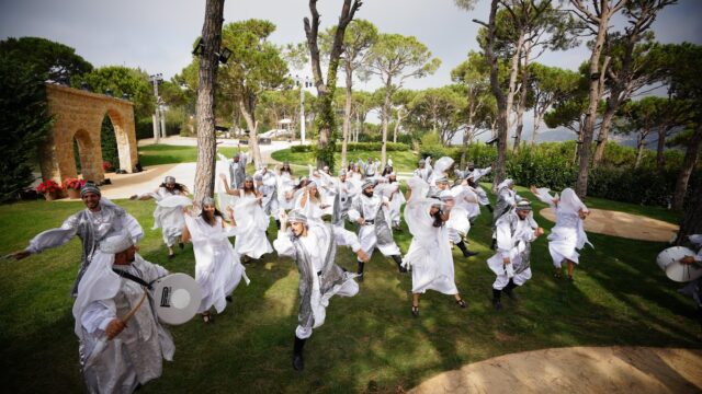 a group of people in white robes dancing in a park