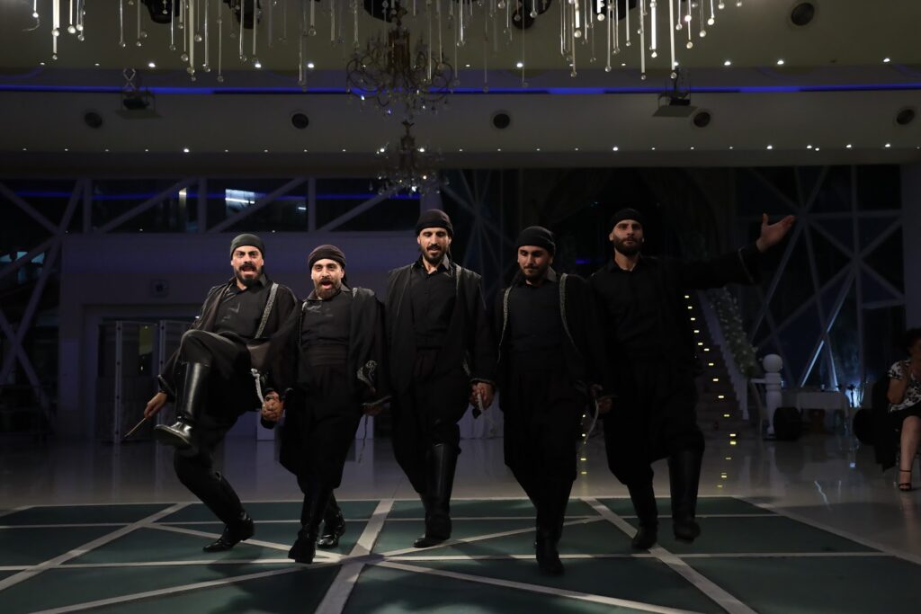 a group of men in black clothes walking on a green carpet