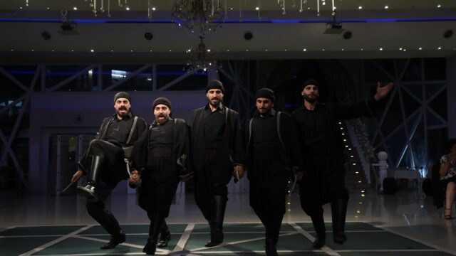 a group of men in black clothes walking on a green carpet