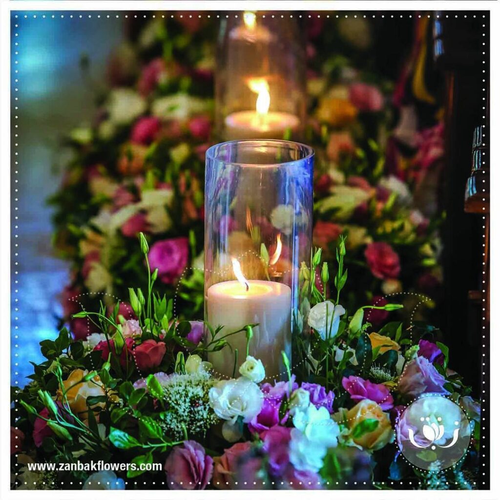 a candle in a glass vase with flowers