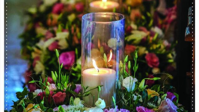 a candle in a glass vase with flowers