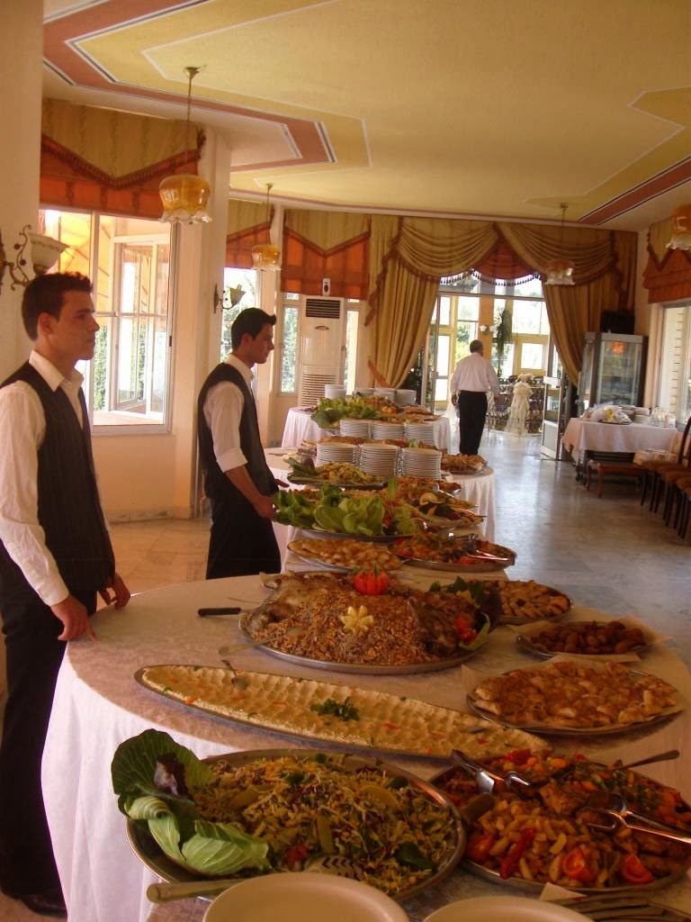 a group of people standing in a room with a table full of food