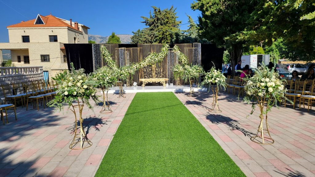 a green carpet with a walkway and chairs and trees