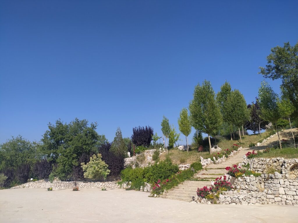 a stone stairs with trees and flowers on a hill