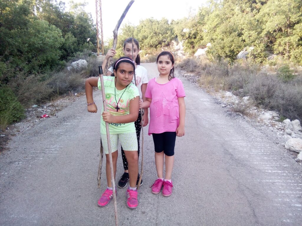 a group of girls standing on a road with sticks