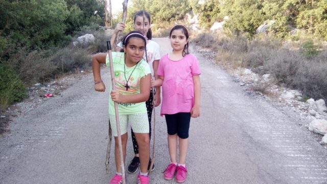 a group of girls standing on a road with sticks