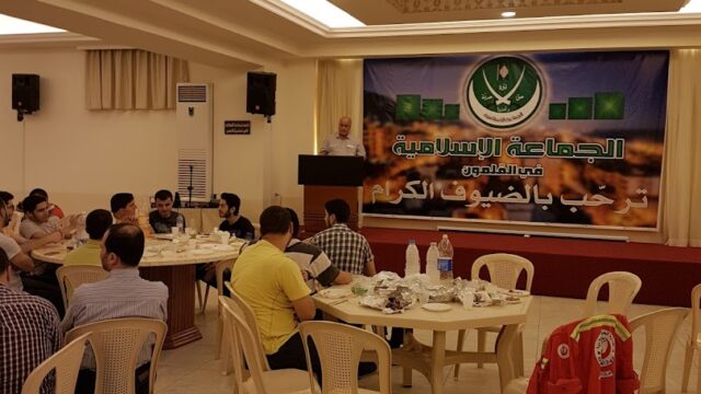 a group of people sitting around tables in a room with a banner