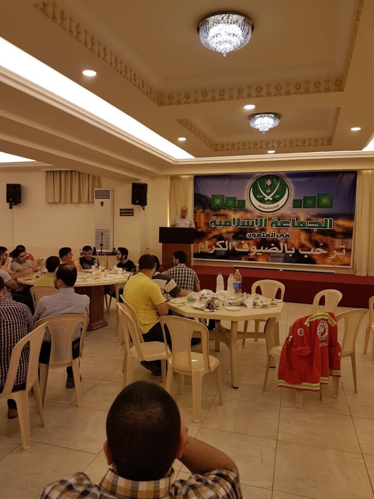 a group of people sitting around tables in a room with a banner