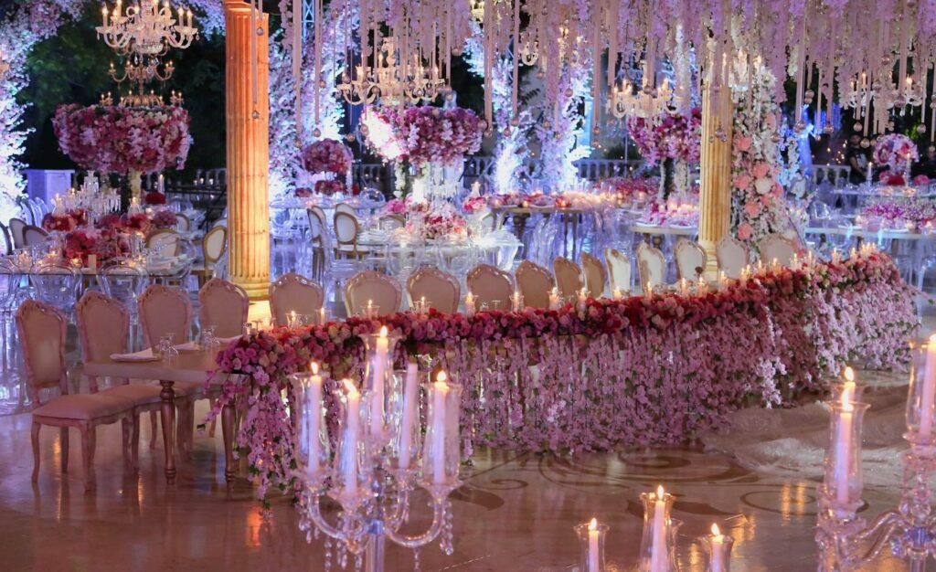 A stunning wedding reception with chandeliers and flowers, beautifully arranged by Al Tawahin .