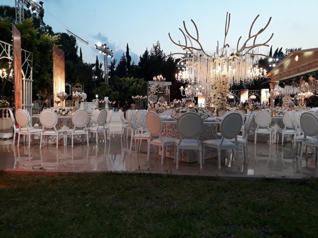 An outdoor wedding reception area with tables and chairs, hosted at Al Tawahin (Kalaa Weddings).