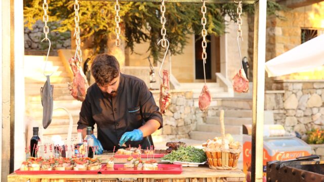 "A man standing at a food stand, representing Baskinta Catering."