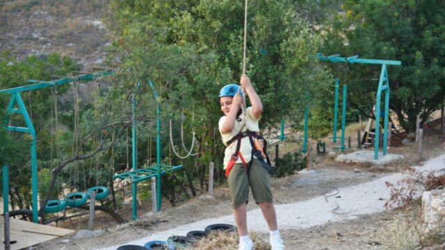A person in a helmet, holding a rope, explores the serene beauty of Bmehrine, Byblos Nature, Cassia, and The INN.