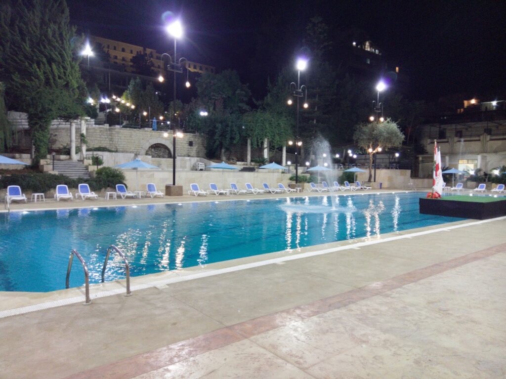 a pool with a fountain and umbrellas