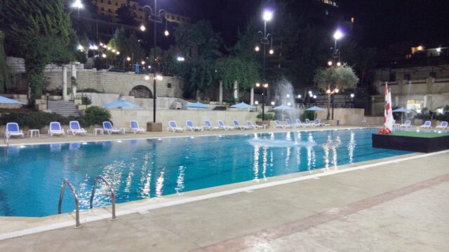 a pool with a fountain and umbrellas