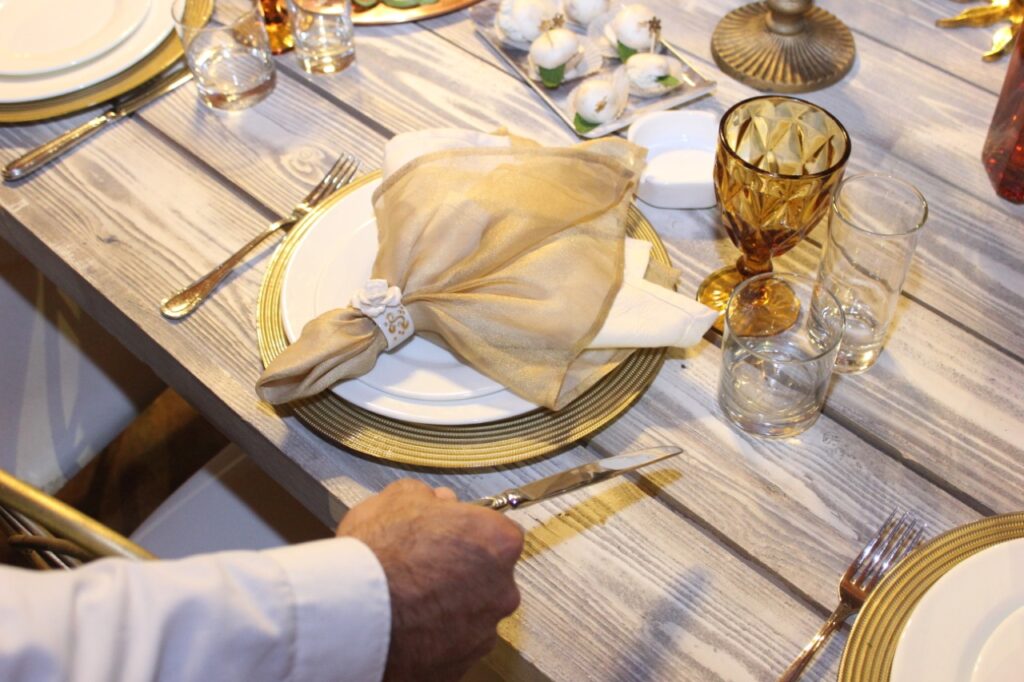 A person holding a knife and fork on a table, enjoying Chaaya's Services.