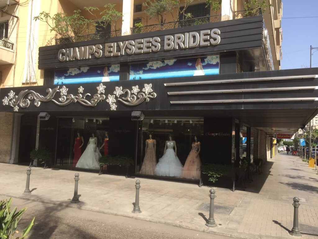 a store front with a sign and dresses in the window