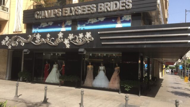 a store front with a sign and dresses in the window