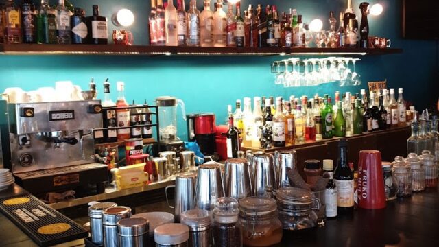 a bar with many bottles and glasses on the shelves