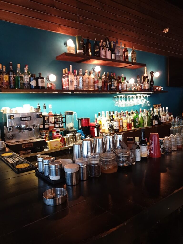 a bar with many bottles and glasses on the shelves