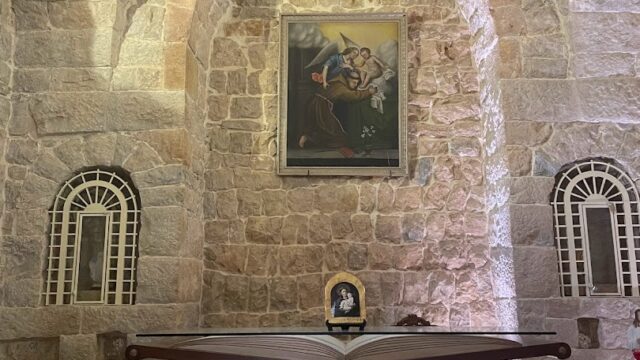 a stone wall with a table and a painting on the wall