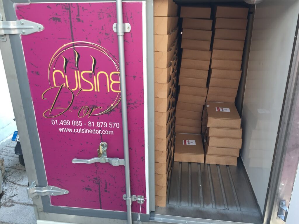 A truck with boxes in it, featuring Cuisine D'or Catering.