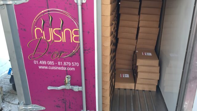 A truck with boxes in it, featuring Cuisine D'or Catering.