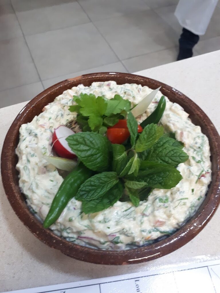 Cuisine D'or Catering prepares a bowl of food with vegetables on top.