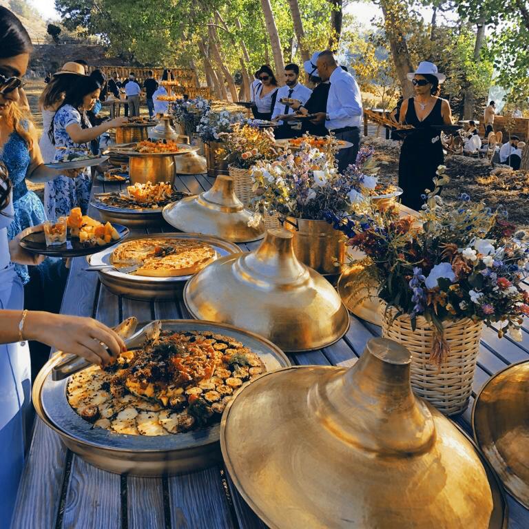 A group of people at a table with food catered by Dalia Catering.