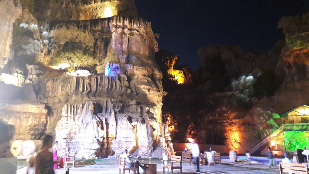 people sitting on benches near a large rock formation