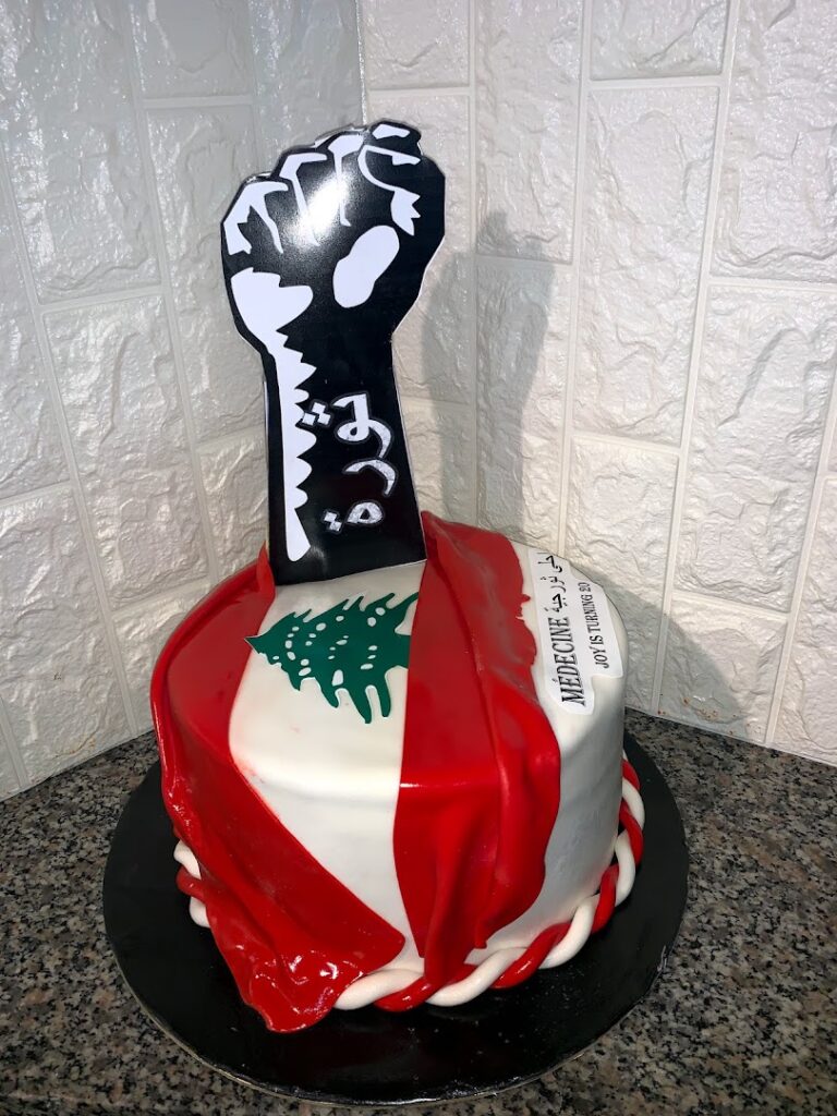 A Exotique Makhlouf-themed cake with a fist on top perfectly captures the essence of uniqueness and boldness.