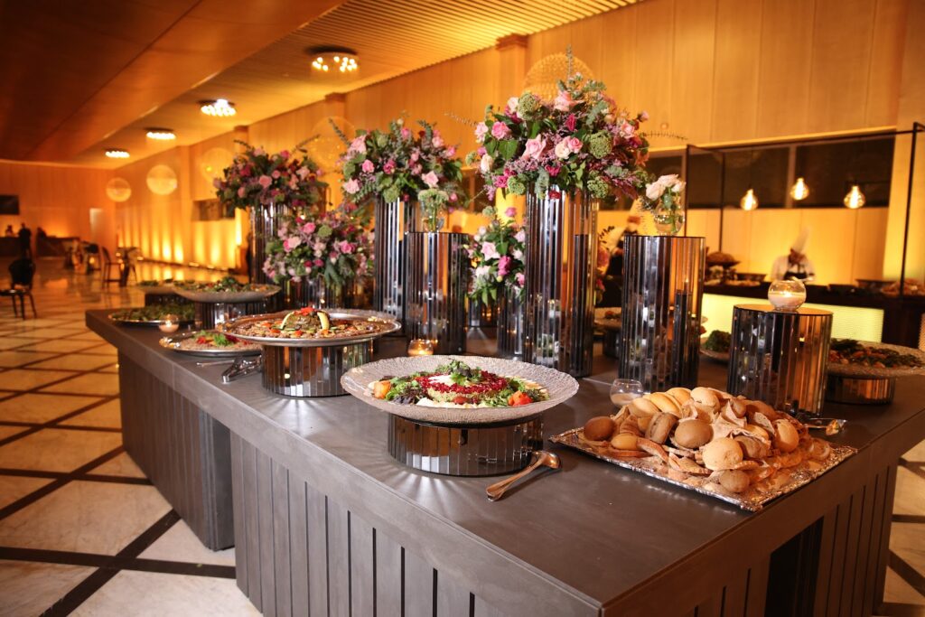 A buffet table with food and flowers catered by Faqra Catering.