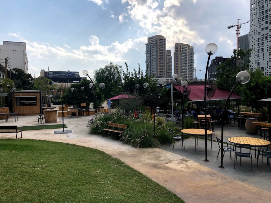 a park with tables and benches and buildings in the background