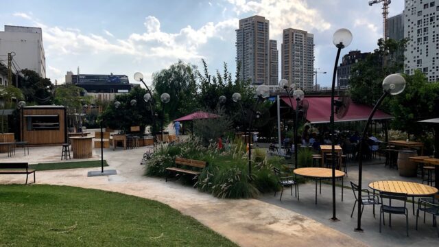 a park with tables and benches and buildings in the background