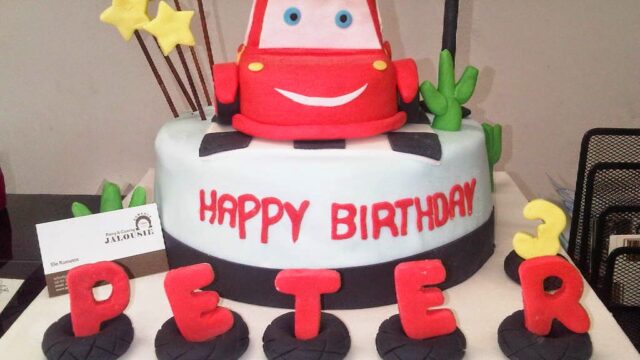 "A birthday cake with a red car and letters beautifully crafted by Jalousie Pastry & Catering."