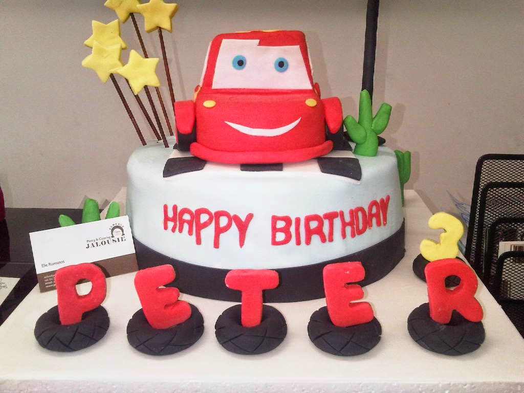 "A birthday cake with a red car and letters beautifully crafted by Jalousie Pastry & Catering."