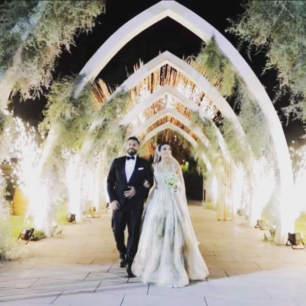 a man and woman walking under a arch with lights