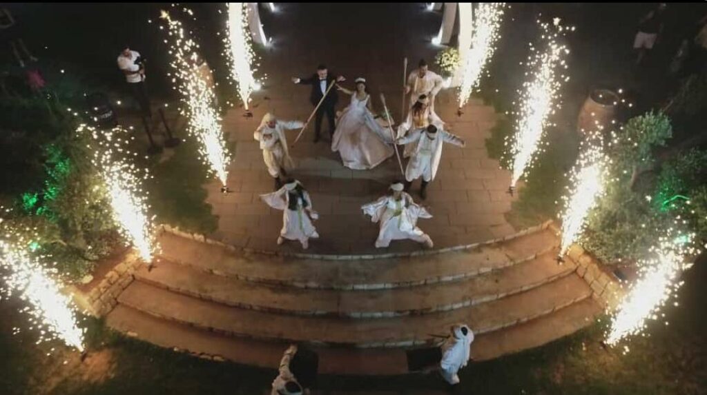 a group of people in white dresses holding sticks and fireworks