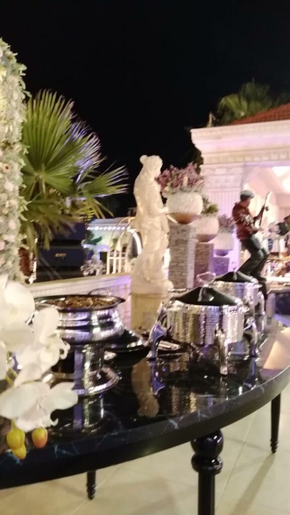 A buffet table with a statue of a man playing a flute adorned with the enchanting atmosphere of "Jardin Du Rêve - Le Rêve".