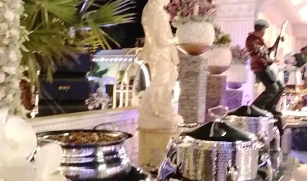 A buffet table with a statue of a man playing a flute adorned with the enchanting atmosphere of "Jardin Du Rêve - Le Rêve".