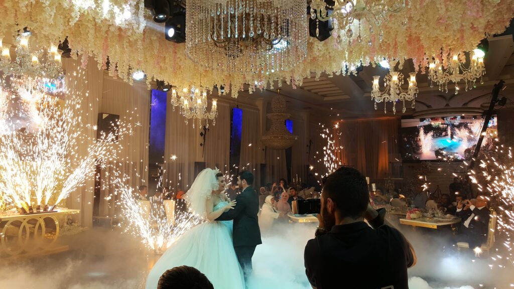 "A bride and groom dancing in Jardin Du Rêve - Le Rêve, a room adorned with vibrant fireworks."