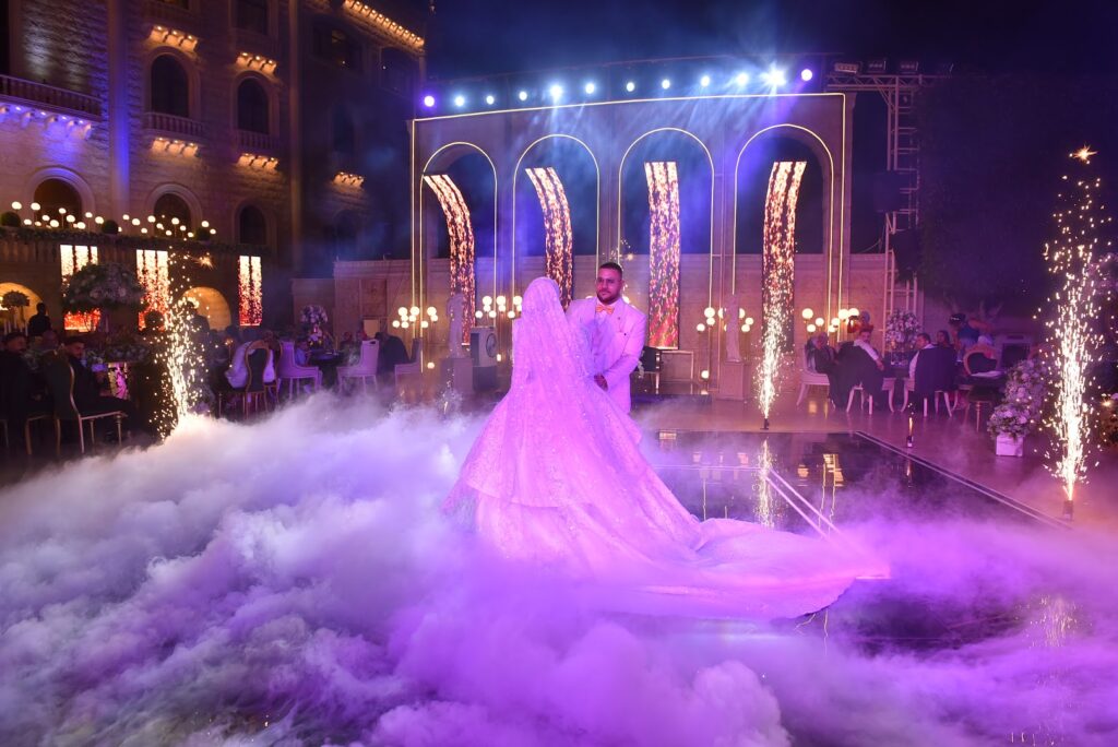 A man and woman, gracefully choreographed, enchantingly dance in front of a stage enveloped in ethereal smoke at Jardin Du Rêve - Le Rêve.